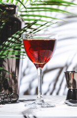 Campbeltown alcoholic cocktail drink with scotch whisky, sherry and liqueur. White marble table with palm leaves and shadows