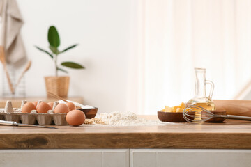 Heap of flour with eggs, butter and whisk for preparing dough on kitchen counter