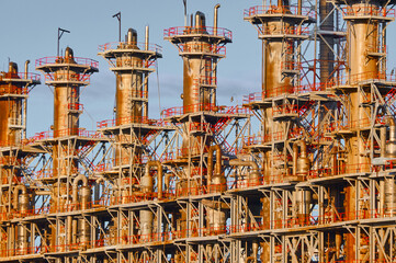Overview of a chemical plant with multiple distillation columns under clear skies during the day showcasing industrial processes