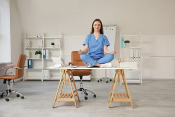 Young female doctor meditating on table in clinic