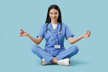 Young female doctor meditating on blue background