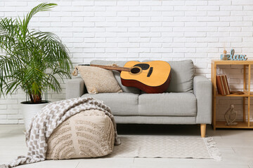 Modern acoustic guitar on grey sofa in stylish living room