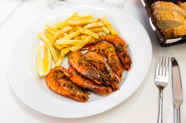 Appetizing baked shrimps with lemon and french fries. High quality photo