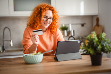 Fototapeta premium woman eat salad and use digital tablet and credit card for payment
