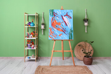 Painting on easel and art supplies in shelving units near green wall