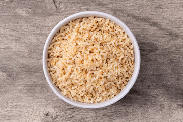 Cooked brown whole rice in a bowl over wooden table