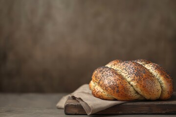 Freshly baked Challah bread loaf with spoppy seeds on a rustic wooden cutting board.