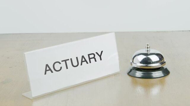Actuary Office or Room with Hand Ringing The Bell on Desk or Table Multiple Times