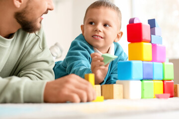 Obraz premium Happy father and his little son playing with colorful cubes at home