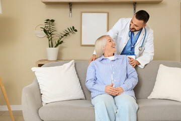 Obraz premium Male doctor hugging mature woman on sofa at home
