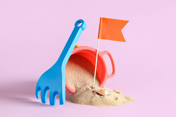 Seashell, sand, flag, toy rake and bucket on pink background