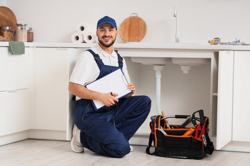Male plumber with clipboard near sink in kitchen