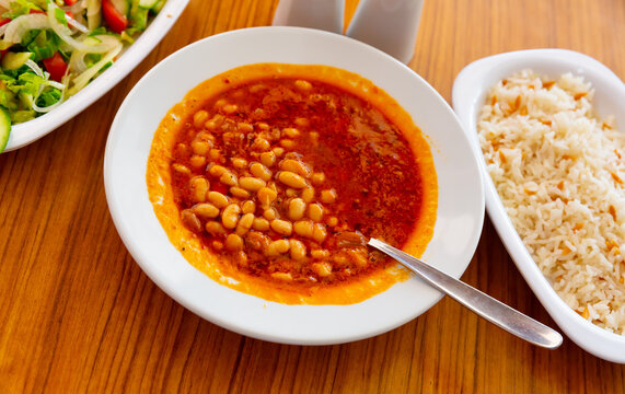 Traditional Turkish Kuru fasulye, spicy stewed bean dish in tomato sauce served with rice and fresh vegetable salad