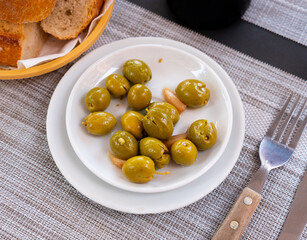 Light and nutritious snack awaits, consisting of handful of pickled green pitted olives and slice of wholesome bran bread.