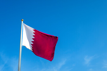 Qatar flag waving in the wind and blue sky background