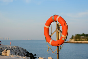 Orange lifebuoy placed at the seaside to prevent drowning