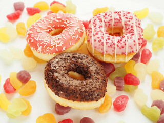 Pink and chocolate donuts on colorful sweet candy jelly. High level of sugar products. Popular international sweets.