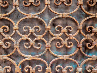 A rusted metal screen with intricate designs. Scene is one of decay and nostalgia, as the rusted metal and intricate designs evoke a sense of history and the passage of time. Old craft example