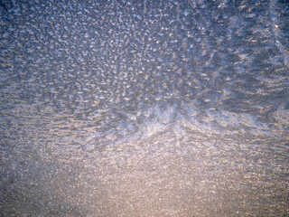 A blue background with a lot of frozen ice on glass texture. The texture is very fine and the color is blue. Cold winter season.