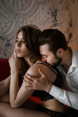 The two sit on a cozy sofa in a dimly lit room, showing a picture of desire intertwined with indifference.