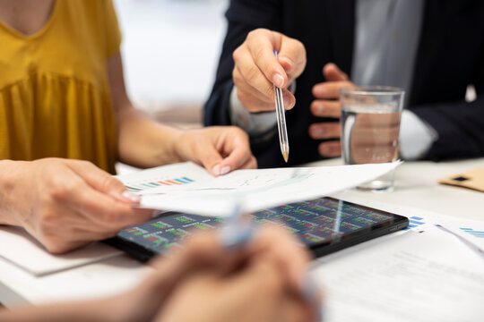 Close up shot of customers in office looking over economic services offers, looking to receive financial markets analysis, investment recommendations and portfolio monitoring