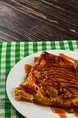 Delicious pastry dessert drizzled with caramel on a checkered tablecloth
