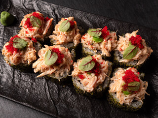 Japanese cuisine. Sushi rolls adorned with roe on a black platter