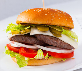 Image of double cheeseburger with beef, tomato, cheese, cucumber and lettuce