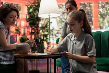 Teenage girl engages in a drawing activity as part of creative therapy session. Counseling with her mother and therapist focuses on using artwork for stress relief and emotional management.