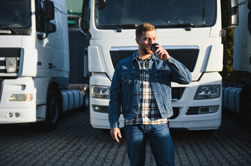 The truck driver drinks coffee. The truck driver rests in the parking lot after work