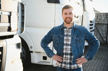 Freight transportation. A handsome truck driver stands on the background of a truck in the parking...