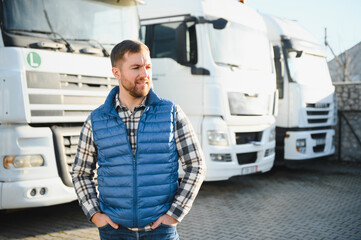 Happy confident male driver standing in front on his truck