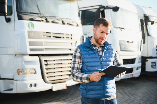 Truck driver checking shipment list while standing on parking lot of distribution warehouse