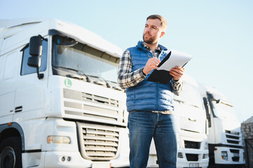 Freight transportation. A handsome truck driver stands on the background of a truck in the parking...
