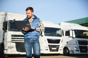 The truck driver uses a laptop to confirm the delivery of the cargo. The concept of freight transportation. Logistics