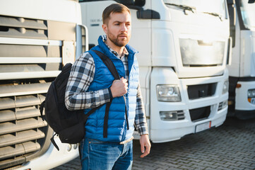 A truck driver with a backpack in a truck parking lot before the start of the work week.
