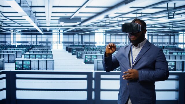 African american developer immersed in virtual reality at data center, doing units maintenance. Technician using VR headset to optimize servers performance, checking operations, camera B