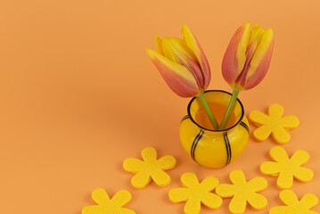 Wunderschöne gelb-orange farbende Tulpen in einer Vase vor einen orangen Hintergrund, Platz für...