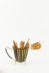 60er Jahre, 70er Jahre, Salzstangen und Salzbrezeln in einem Salzstangenspender, der gelbe und schwarze Streifen hat, isoliert, weißer Hintergrund, platz für text