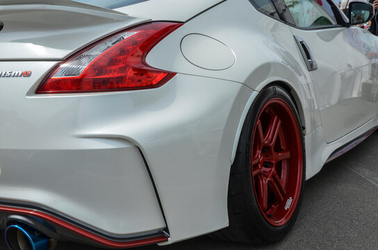 White sports car Nissan 370Z displaying red wheels and fine body details, emphasizing the vehicle's sporty and modern characteristics