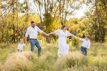 Fototapeta premium Family of four walking together through lush field in golden afternoon light