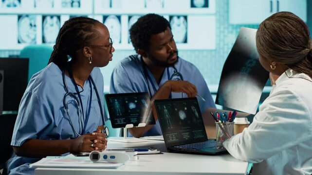 African american general practitioner leading a healthcare team in a cabinet, analyzing MRI imaging results and providing accurate diagnosis and effective treatment. Medical facility. Camera A.