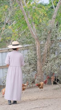 Granjera alimentando gallinas en el campo 