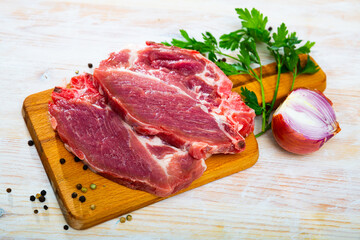 Fresh raw pork chop steak on wooden background with herbs