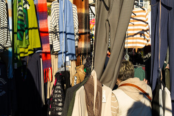 Lady hiding among numerous colorful clothes at an outdoor flea market in Galicia, Spain, on a sunny...