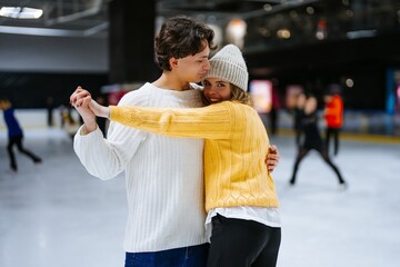Couple enjoying ice skating together at a rink during winter