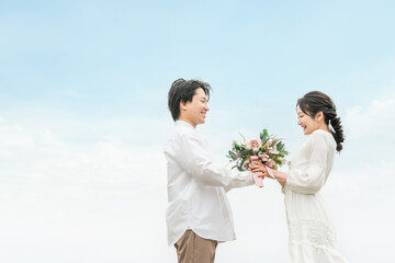 ブーケを渡す新郎と受け取る新婦・カジュアルウェディング・カップル・恋人・夫婦のイメージ
