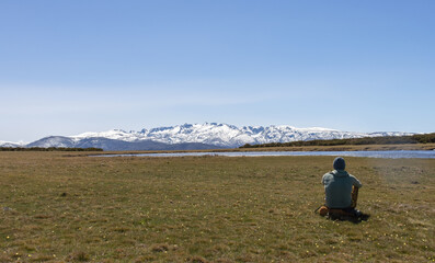 Obraz premium person contemplating a snow-capped mountain range in front of a mountain lake, mountain scene