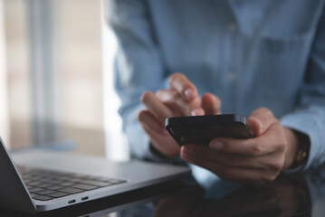 Close up, business woman using mobile smart phone searching the information, surfing the internet during working on laptop computer at office, social media marketing