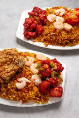 Sweet and sour chicken with fried rice, shrimp, pork ribs, on white plate with marble background